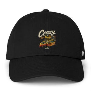 Può includere: Cappellino da baseball nero con visiera curva. Il cappellino presenta il testo "Crazy as a Road Lizard" in un font in stile vintage, insieme a un'illustrazione di una lucertola con occhiali da sole. Il numero "47" è sul lato.