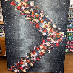 May include: A large quilt with a dark gray background and a cascading floral design. The floral pattern features red, pink, and white flowers. The quilt has a quilted pattern and gold speckles.
