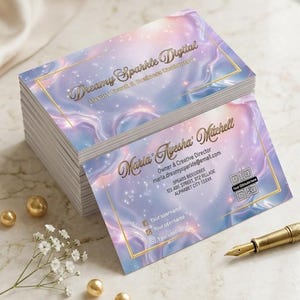 Op de afbeelding: Een stapel rechthoekige visitekaartjes met een pastelpaarse en blauwe gemarmerde achtergrond, voorzien van goudfolie tekst met Dreamy Sparkle Digital, Luxury Event & Business Stationery en Maria Ayesha Mitchell, Owner & Creative Director.