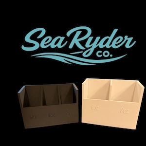 May include: Two rectangular containers, one dark brown and one off-white, with the text "Sea Ryder Co." above them. The dark brown container has three compartments with "3oz", "6oz", and "10oz" labels. The off-white container has two compartments with "6oz" and "8oz" labels.