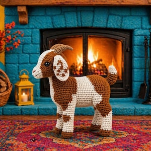 May include: A handmade crochet goat in brown and white stands on a colorful rug in front of a fireplace. The goat has detailed features, including horns and patterned ears. A basket of logs and a lantern are also visible.