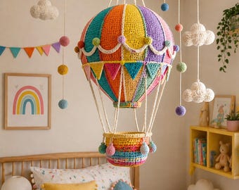 Pode incluir: Uma lâmpada de balão de ar quente de crochê colorida, com listras vibrantes de laranja, amarelo, verde e roxo, pendurada no teto. A lâmpada inclui uma cesta e é suspensa por cordas brancas. Pompons decorativos e ornamentos em forma de nuvem completam a decoração do berçário.