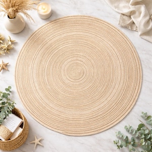 May include: A large, circular beige placemat with a concentric spiral pattern. The placemat is made of woven material. Decorative elements include a vase with dried flowers, a lit candle, and starfish. The placemat's diameter is approximately 30 cm.