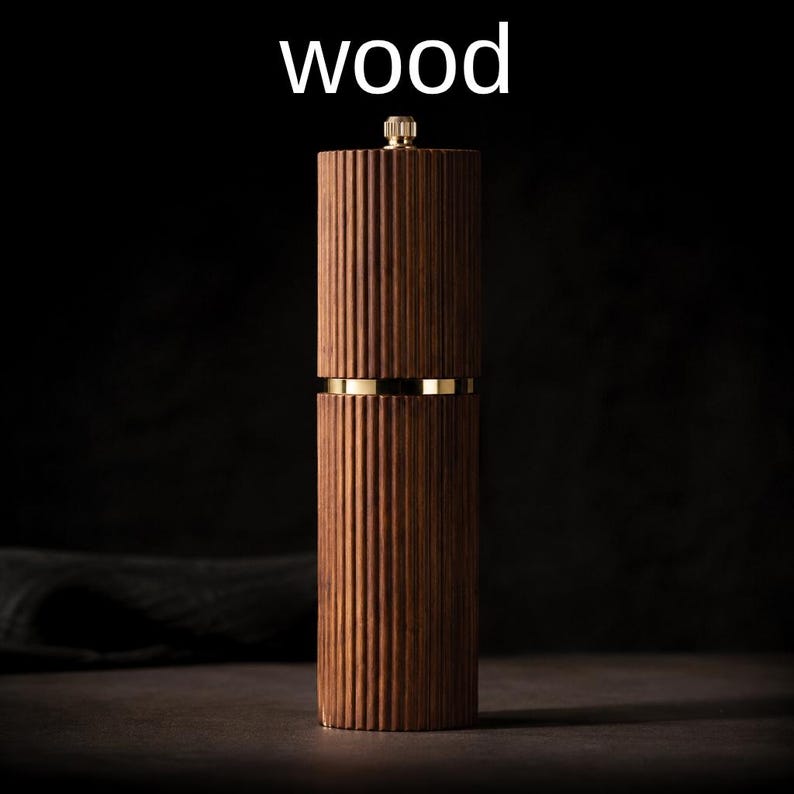 May include: A wooden pepper mill with a ribbed design. The mill is a dark brown color with gold-colored accents. The word "wood" is written in white at the top of the image. The mill is a kitchen utensil.