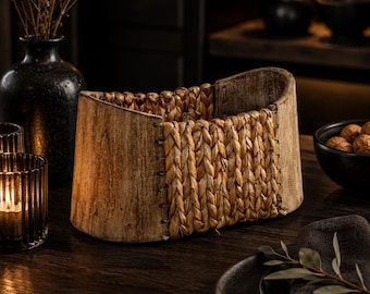 May include: A decorative wooden basket with a woven central panel. The basket is made of light brown wood with a natural grain, and the woven section is a light tan colour. It sits on a dark wooden table.
