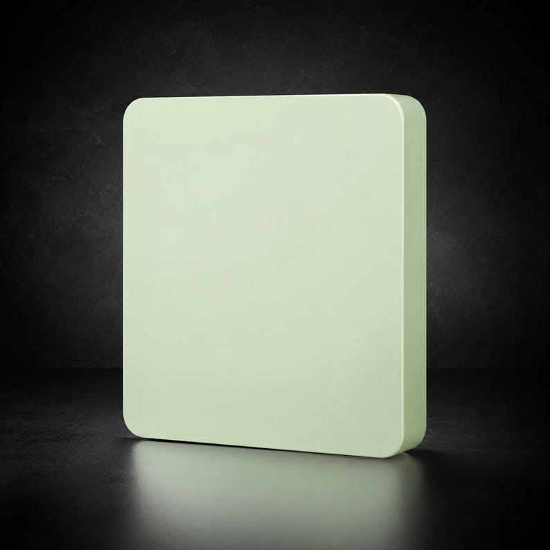 May include: A square, pale mint green block with rounded corners. The object features a smooth, solid surface and a thick, uniform profile, presenting a clean, geometric shape that stands upright on its base with a consistent matte finish.