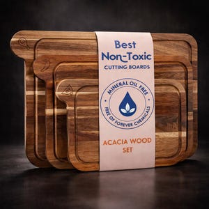 May include: A set of three acacia wood cutting boards with a natural wood grain finish. The boards have a rectangular shape with a handle and a juice groove. The packaging reads "Best Non-Toxic Cutting Boards" and "Acacia Wood Set".
