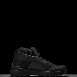 May include: Black hiking boot with a high-top design. The boot features a mesh and leather upper, a padded collar, and a thick, textured sole. The boot is designed for outdoor activities and provides ankle support. The boot measures approximately 6 inches in height.
