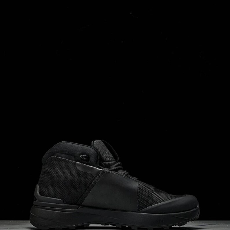 May include: Black hiking boot with a high-top design. The boot features a mesh and leather upper, a padded collar, and a thick, textured sole. The boot is designed for outdoor activities and provides ankle support. The boot measures approximately 6 inches in height.