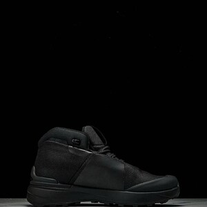 May include: A black high-top hiking boot with a mesh and leather upper. The boot has a thick, textured sole and a padded collar. The boot is designed for outdoor activities and provides ankle support.