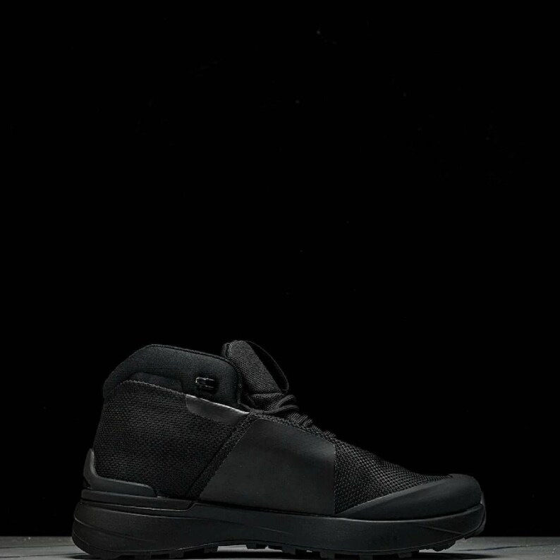 May include: A black high-top hiking boot with a mesh and leather upper. The boot has a thick, textured sole and a padded collar. The boot is designed for outdoor activities and provides ankle support.