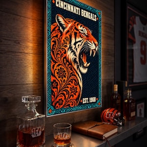 Könnte beinhalten: Ein rechteckiger Wandkunstdruck mit einem brüllenden Tiger mit orangefarbenen und schwarzen Blumenmustern. Der Text lautet CINCINNATI BENGALS und EST. 1968. Das Design ist von einem dünnen Rand mit geometrischen türkisfarbenen Akzenten umgeben.