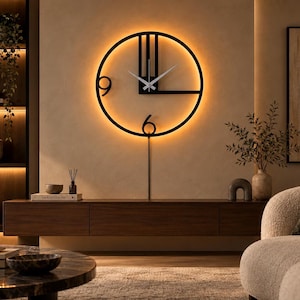 Peut inclure: Une horloge murale circulaire en métal noir au design ouvert et minimaliste, comportant les chiffres 9 et 6, de fines aiguilles argentées et une tige de support verticale. L'horloge est éclairée par l'arrière par un anneau lumineux LED chaud.