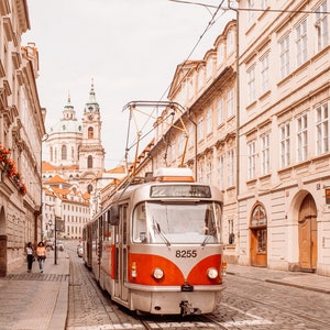 May include: A red and silver tram with the number 8255 on the front, traveling down a cobblestone street in Prague, Czech Republic. The tram is labeled "22" and "Hradcany Stra&scaron;nice".