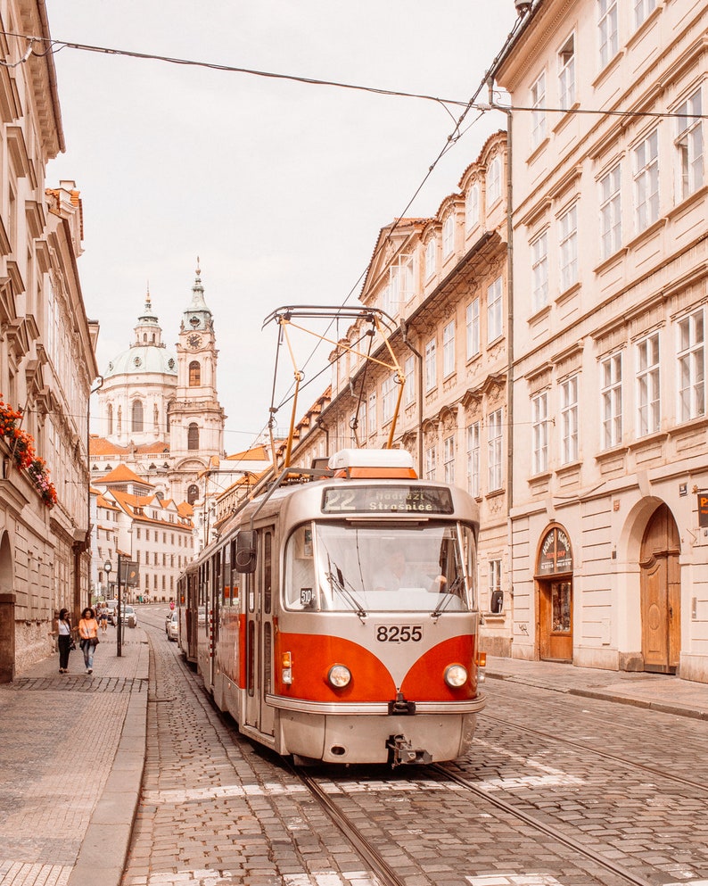 May include: A red and silver tram with the number 8255 on the front, traveling down a cobblestone street in Prague, Czech Republic. The tram is labeled "22" and "Hradcany Stra&scaron;nice".