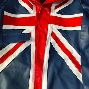 May include: A blue jacket featuring a prominent Union Jack flag design in red and white. The garment has a collared neckline, a central button-down closure, and a horizontal flap detail on the right side, all constructed from a smooth material.