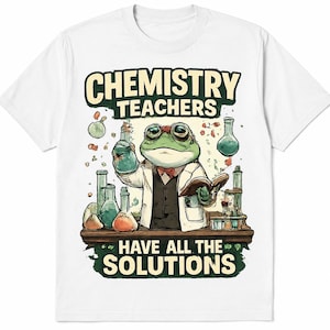 May include: White t-shirt with a cartoon frog in a lab coat and glasses, holding a beaker and a book. The text reads "CHEMISTRY TEACHERS HAVE ALL THE SOLUTIONS" in a green and cream design. Various lab equipment is also shown.