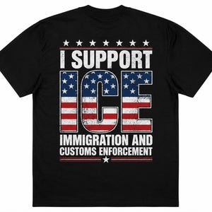 以下が含まれることがあります： 黒の半袖Tシャツで、I SUPPORT ICE IMMIGRATION AND CUSTOMS ENFORCEMENTというテキストのグラフィックプリントが施されています。ICEの文字はダメージ加工されたアメリカ国旗の模様で埋め尽くされ、白い星と水平線で囲まれています。
