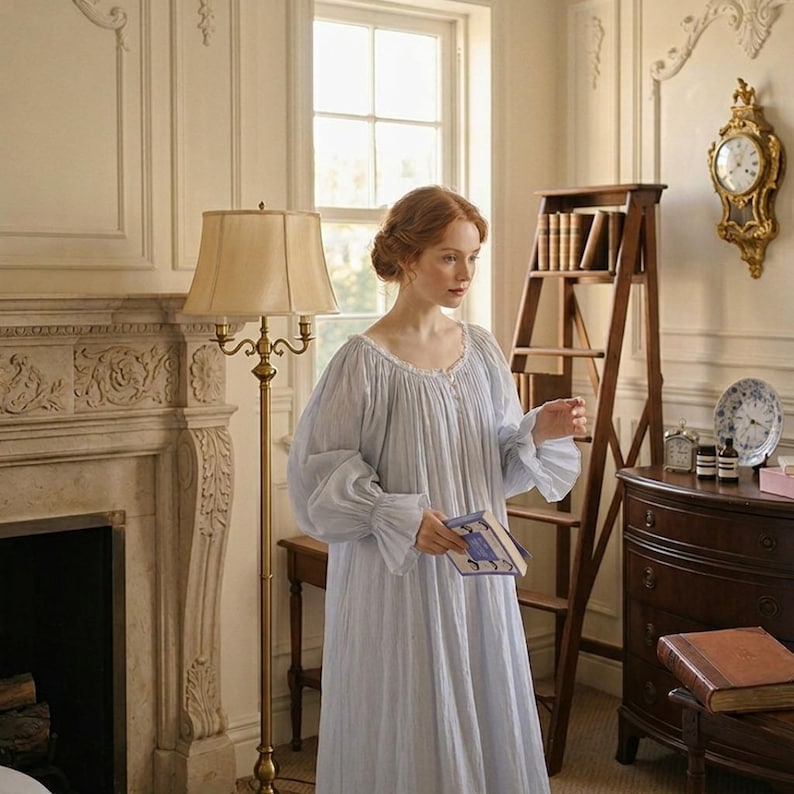 May include: A light blue nightgown with long, ruffled sleeves and a round neckline. The woman in the image is holding a book. The room features a fireplace, a wooden ladder, and a gold-framed clock.