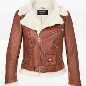 Peut inclure: Veste en cuir marron avec col et doublure en peau de mouton blanche. La veste a une fermeture éclair, plusieurs poches et une ceinture à la taille. L'étiquette indique "MAVERICK JACKET".