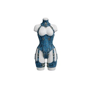 Op de afbeelding: Een blauwe corset- en jarretelset met slangenpatroon op een mannequin. Het korset heeft een hoge hals, halterbandjes en goudkleurige hardware. De jarretelbandjes zijn bevestigd aan shorts en dijbeenbanden, eveneens met gouden hardware.