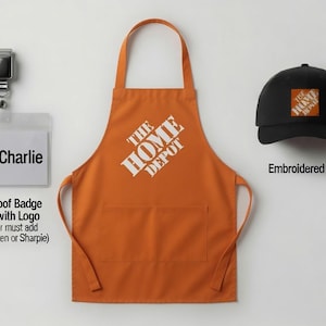 May include: An orange apron with The Home Depot logo in white, a black baseball cap with an embroidered orange and white logo, and a clear plastic badge holder with a metal clip featuring The Home Depot logo and the printed name Charlie.