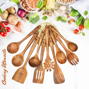 May include: A collection of wooden cooking utensils, including spoons, spatulas, and a pasta fork, arranged on a white surface. The utensils are made of a light brown wood and are surrounded by fresh vegetables and grains. The text "Cooking Utensils" is visible.