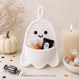 Peut inclure: Une pochette murale en crochet blanc en forme de fantôme avec une boucle de suspension, deux yeux circulaires noirs et une petite bouche brodée. La pochette contient des bonbons emballés. Texte : Finished Size: 4 in x 5.5 in (10,2 cm x 14 cm).