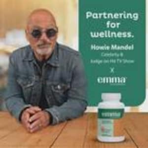 May include: An image featuring Howie Mandel with a bottle of vitamins. The bottle is white with a green label and the text "emma". The text "Partnering for wellness" is above the text "Howie Mandel". The image is on a wooden surface.