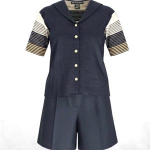 May include: A navy blue short-sleeve shirt with a sailor-style collar and gold buttons, paired with matching navy blue pleated shorts. The shirt sleeves feature horizontal stripes in white, grey, and tan. The inner label reads BEYOND RETRO.