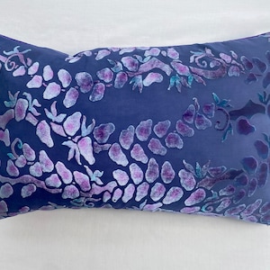 May include: A blue velvet pillow with a floral pattern in shades of purple and teal.