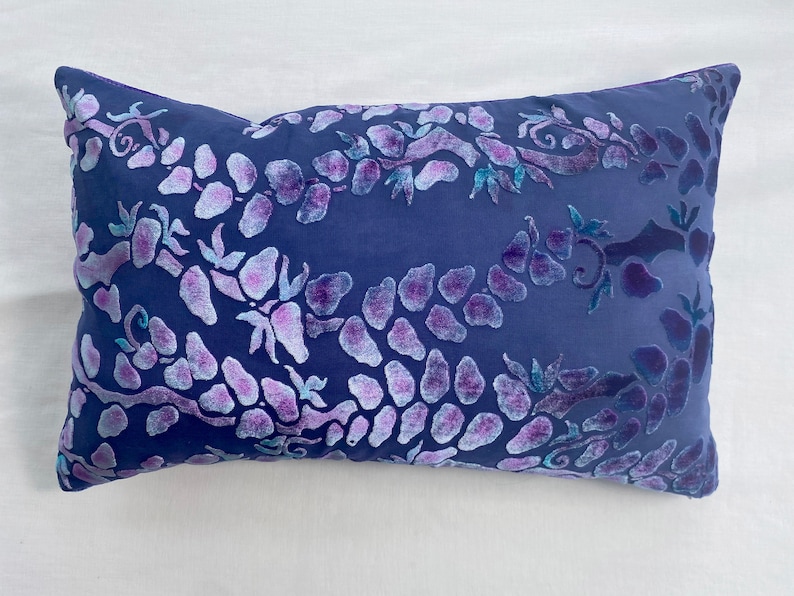 May include: A blue velvet pillow with a floral pattern in shades of purple and teal.
