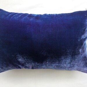 May include: A deep blue velvet pillow with a soft, plush texture. The pillow is rectangular and has a subtle sheen.