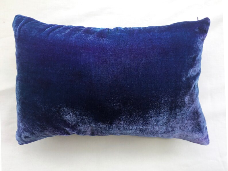 May include: A deep blue velvet pillow with a soft, plush texture. The pillow is rectangular and has a subtle sheen.