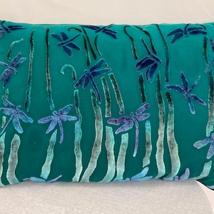 May include: Teal velvet pillow with an embroidered dragonfly pattern. The dragonflies are in shades of blue and green.