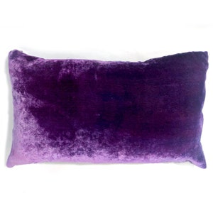 May include: A purple velvet pillow with a soft, plush texture. The pillow is rectangular and has a subtle sheen.