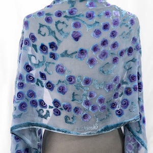 May include: A sheer blue silk scarf with a velvet floral design in shades of purple. The scarf has a scalloped edge and the text "Sherri Love" is visible on the bottom edge.