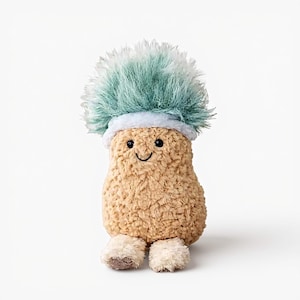 May include: A plush mushroom toy with a smiling face, light brown body, and fluffy blue-green cap. The toy has small, cream-colored feet and a light blue band around the base of the cap. The background is plain white.