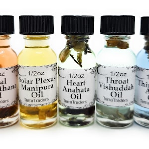 May include: Seven small glass bottles with black caps, each containing a different colored liquid and herbs. The bottles are labeled with the names of the seven chakras: Root, Sacral, Solar Plexus, Heart, Throat, Third Eye, and Crown. Each bottle is labeled with "1/2oz Oil" and "Terra Traders".