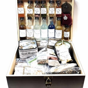 May include: A wooden box filled with various items for spell casting, including herbs, oils, candles, and a tin of Seer Magick hand-poured box candles. The box has a lock and key.