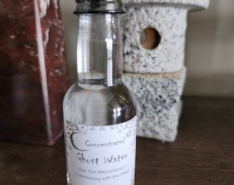 May include: A clear glass bottle with a black cap and a white label that reads "Concentrated Ghost Water. Use For Necromancy/Communing with the Dead. 1.7 OZ TerraTraders.com"
