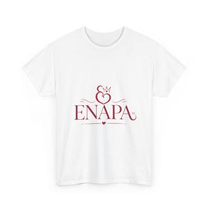 Puede incluir: Camiseta blanca con un gráfico burdeos. El gráfico presenta la palabra "ENAPA" con un diseño de corazón y corona encima. Un pequeño corazón está debajo de la palabra. La camiseta está hecha de un material suave y cómodo.