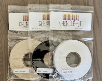 May include: Three individual clear plastic bags each containing a spool of Chenille-It blooming bias tape. The spools are labeled BB32 Natural, BB47 Black, and BB31 White. Each package features a logo with colorful zig-zag lines and text.
