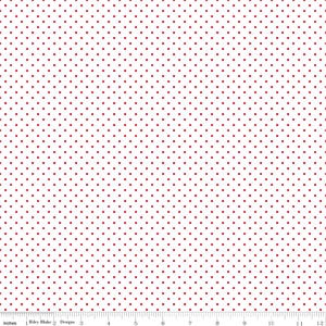 May include: A white fabric featuring a repeating pattern of small, evenly spaced red polka dots. A ruler is visible at the bottom edge, showing a scale in inches from 0 to 12, with the text Riley Blake Designs printed near the start.