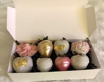 Elegante confezione regalo di fragole ricoperte di cioccolato, con decorazioni floreali color oro rosa e composizione commestibile.
