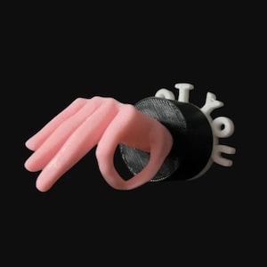 May include: A pink hand emerging from a black circular object, with the white text "I Got You" attached. The hand is in a gesture, with the thumb and index finger forming a circle. The background is black.