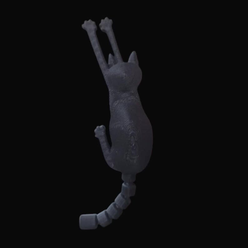 May include: A dark gray cat-shaped wall hook with its front paws raised. The cat's tail is segmented, and the hook is designed to be mounted on a wall. The cat is in a climbing pose, with a textured surface.