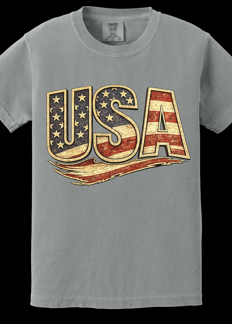 May include: Gray t-shirt with the word "USA" in a distressed design. The letters are filled with the American flag's stars and stripes. A distressed red and gold banner is below the letters.