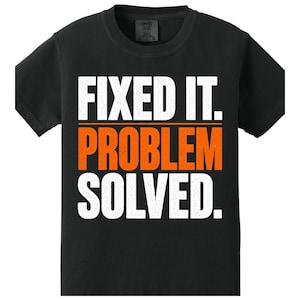 Può includere: T-shirt nero con la scritta "FIXED IT. PROBLEM SOLVED." in lettere bianche e arancioni. La maglietta ha un girocollo e maniche corte. Il testo è centrato sulla parte anteriore della maglietta.