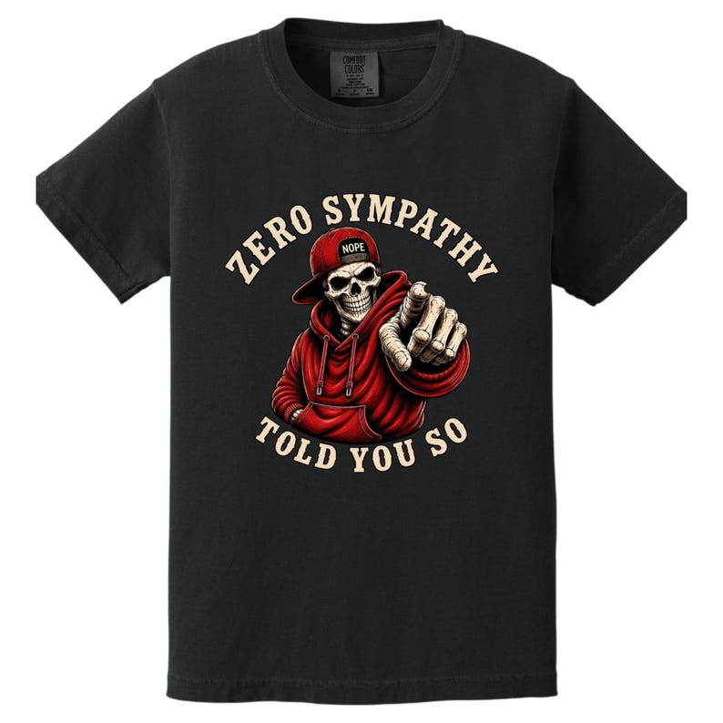 May include: Black t-shirt featuring a skeleton wearing a red hoodie and a baseball cap with the word "Nope". The skeleton is pointing with its index finger. The text "ZERO SYMPATHY TOLD YOU SO" is printed around the skeleton.